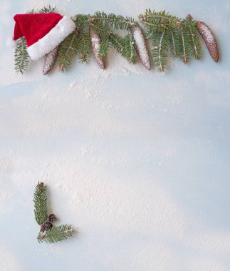 Yeni yıl, yeni yıl arkaplanı. Karda açık mavi arka planda çam kozalakları ve Noel Baba şapkası olan bir dal parçası..