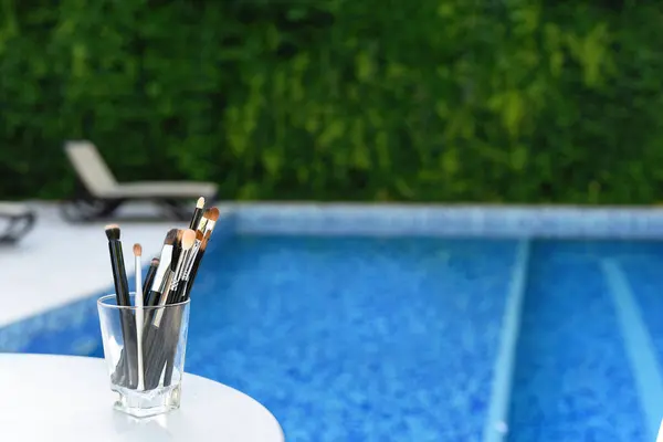 Makeup brushes on a background of a swimming pool