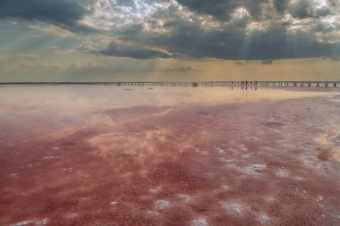 Gül suyu ve tuzlu tuzlu tuz gölü. Güneşli bir günde muhteşem bir tuz gölü manzarası. Güneş ışınlarıyla dramatik gökyüzü.