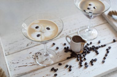 Kahve çekirdekleri ile süslenmiş martini bardağında Espresso Martini kokteyli ve parlak bir iç mekanda kahve likörü.