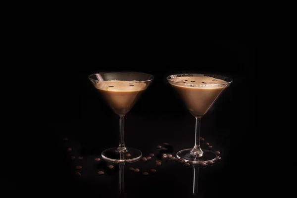 Espresso Martini cocktail in a martini glass decorated with coffee beans on a black background in a low key.