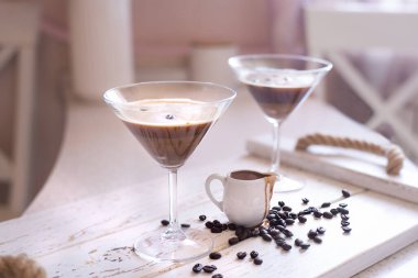 Kahve çekirdekleri ile süslenmiş martini bardağında Espresso Martini kokteyli ve parlak bir iç mekanda kahve likörü.