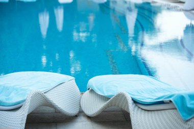 Havuz kenarında güneşli yataklar. Havuzdaki suyun yanında dinleniyorum..