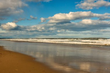 Tüylü bulutların olduğu güneşli bir günde okyanus kıyısı. Kıyıdaki suda gökyüzünün yansıması. ABD 'nin Atlantik kıyıları