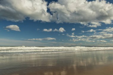 Tüylü bulutların olduğu güneşli bir günde okyanus kıyısı. Kıyıdaki suda gökyüzünün yansıması. ABD 'nin Atlantik kıyıları