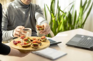 Ofisteki işyerinde atıştırmalık. Masaüstündeki tepsiden sandviç alan çalışanların elleri