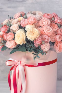 Büyük bir buket pembe gül pembe bir karton kutuda gri bir arka planda..
