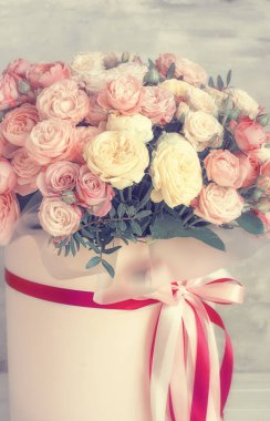 Gri arka planda pembe karton bir kutuda pembe güller. Soluk tonlar