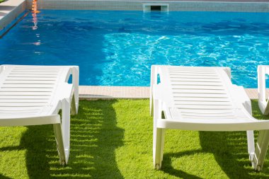 Güneşli bir günde havuz kenarında plastik güneşlenirler.