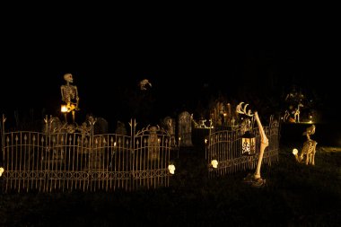 Cadılar Bayramı dekorasyonunun karanlık gece fotoğrafı. Karanlıkta parlayan mezarlık ve iskeletler