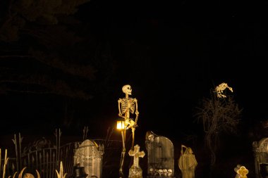 Cadılar Bayramı dekorasyonunun karanlık gece fotoğrafı. Karanlıkta parlayan mezarlık ve iskeletler