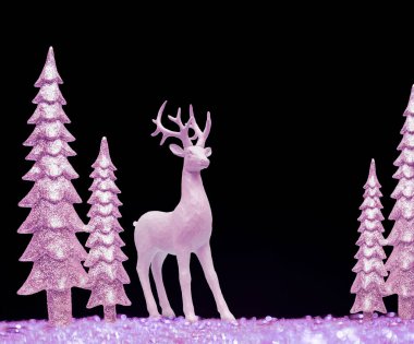 Pembe parlak oyuncak Noel ağaçları ve arka planda pembe bir geyik. Yeni yıl arkaplanı.