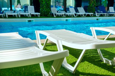 Güneşli bir günde havuz kenarında plastik güneşlenirler.