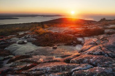 Okyanusa bakan bir dağda gün doğumu ve uzaktaki binalar. Cadillac Dağı, Amerika 'nın doğu kıyısındaki en yüksek nokta. Acadia Ulusal Parkı. İnanılmaz güzel bir manzara. 