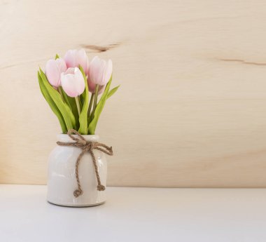 Basit bir doğal arka planda seramik vazoda suni pembe laleler. boş alan