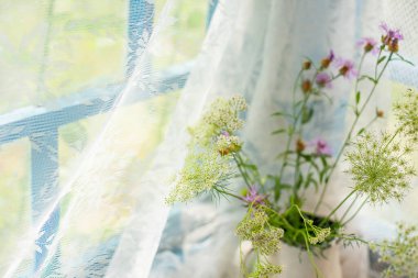 Bir köy evinin penceresinde bir buket yaban çiçeği.