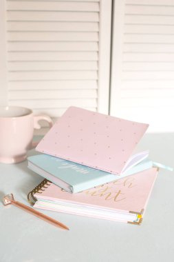 defterler, fincan, günlük, pastel mavi bir masaya yerleştirilmiş pembe sakura çiçekleri. Sahne sakin, stil ve yaratıcılık dolu, iş ve yaratıcılık için ideal..