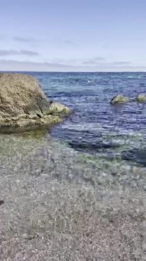 Deniz kıyısında güneşli bir gün. berrak, temiz su ve suda taşlar.