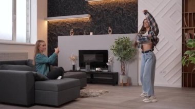 Akıllı telefon kamerasıyla video kaydeden iki kızın yan görüntüsü. Genç ve güzel bir kadın, oturma odasında ya da stüdyoda hip hop dansı yapan arkadaşını vuruyor. Yüksek kaliteli görüntüler