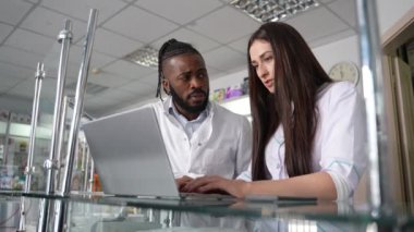 4K yüksek kaliteli beyaz kadın ve koyu tenli bir erkeğin perakende satış mağazasında envanter ve denetimi yönetmek için dizüstü bilgisayarda çalışmalarına ait görüntüler. Etkili yönetim ve takım çalışması