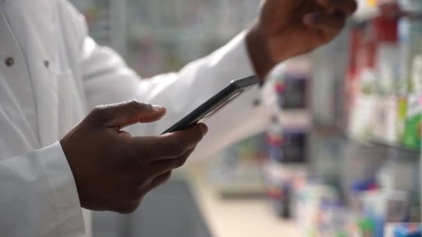 필름의 약국에서 포장을 검사하기 스마트폰을 사용하는 남성의 피부가 약사의 의약품 로열티 프리 스톡 비디오