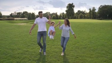 Melez bir aile birlikte harika vakit geçiriyor, neşe ve mutluluk dolu, güneşli bir yaz parkında açık havada oynuyorlar. 4k yüksek çözünürlük