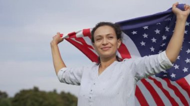 Kutlamaların ortasında gururla ayakta duran bir kadın, 4 Temmuz 'da Amerikan bayrağıyla birlik ve özgürlüğü simgeliyor. 4k yüksek çözünürlük