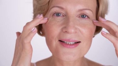 Cildine sevgiyle bakan, özsevginin ve kendinden emin yaşlanmanın özünü kucaklayan orta yaşlı çekici bir kadının yakın portresi.