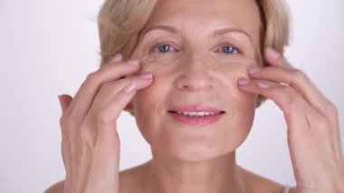 Olumlu, güzel, yaşlanan kadın cildine iyi bakıyor. Yaşlanma karşıtı cilt bakım ürünleri. Özgüven, özgüven, iç güç.