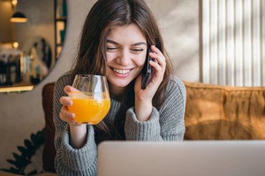 Çekici genç bir kadın telefonda konuşuyor ve sabahın erken saatlerinde dizüstü bilgisayarla çalışıyor..