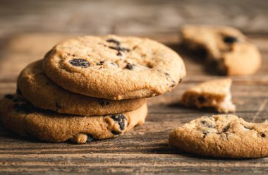 Klasik çikolata parçalı kurabiyeler ahşap arka plana karşı. Tatlı, pişirme ve tatlı yemek kavramı..