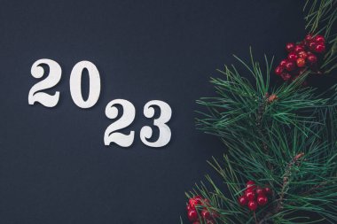 2023 rakamlarıyla Noel siyah arka planı ve dekorasyon ayrıntıları, düz döşeme, minimal tasarım.