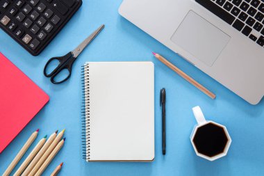 Düz konum, not defteri, dizüstü bilgisayar ve kırtasiye, mavi arkaplan, kopyalama alanı.