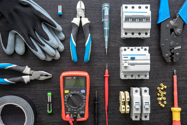 Flat lay composition with electrical tools on wooden background.