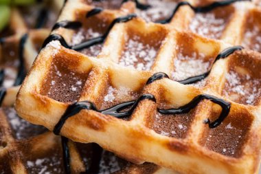 Yakın plan, iştah açıcı Belçika waffleları çikolata serpiştirilmiş, yumuşak odaklı, yiyecek arka planı.
