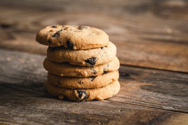Klasik çikolata parçalı kurabiyeler ahşap arka plana karşı. Tatlı, pişirme ve tatlı yemek kavramı..