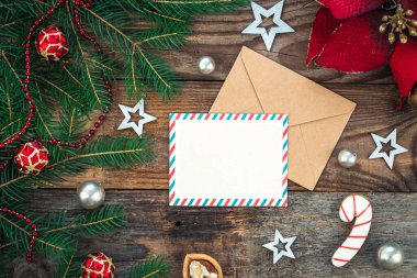 Boş kağıt, zarf, ladin dalları ve ahşap arka planda samimi Noel dekorasyonu ayrıntıları, düz uzanma.