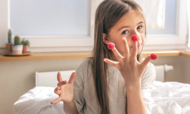 Parmaklarında ahududu olan komik küçük kız sabahları yatakta oturuyor, sağlık ve vitamin kavramı..