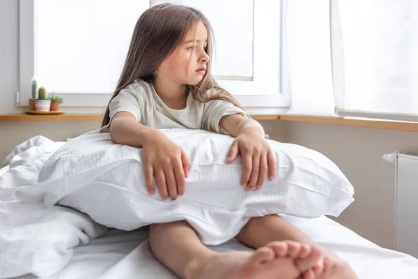 stock image Adorable little girl with pillow in bed early in the morning.