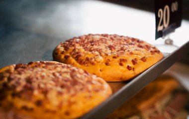 Fırındaki tezgahın üstünde yeni pişmiş mini pizza. Arka planda bulanık bir görüntü..