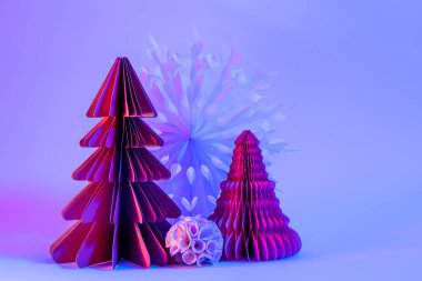 Minimalist yaratıcı Noel ve yeni yıl sanat kompozisyonu. Mavi arka planda, neon ışıklı kağıt köknar ağaçları. Boşluğu kopyala, metin için boşluk.