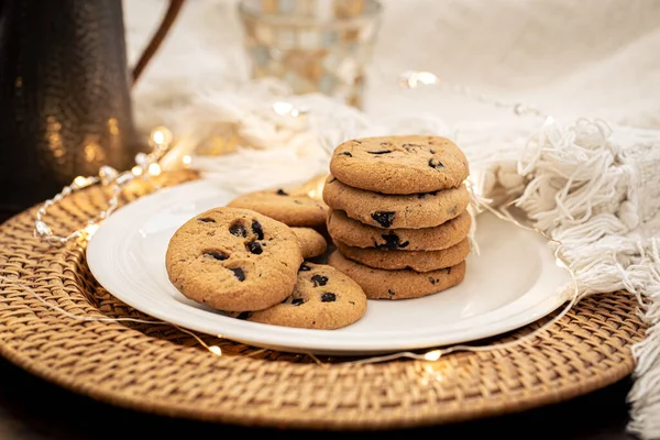 Close-up of chocolate chip cookies on a plate on a blurred background with a garland.