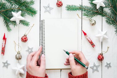 Beyaz not defteriyle birlikte Noel arkaplanı. Güzel kadın elleri, bir kız planlar yazar, gelecek için hedefler, düzlük.