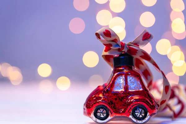 Close-up, car-shaped Christmas toy on a blurred background with bokeh, copy space.
