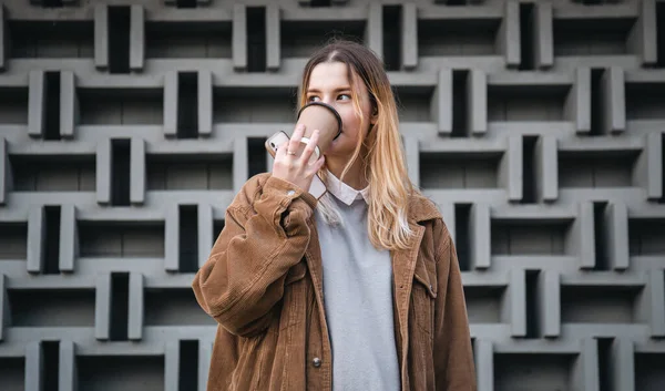 Egy Fiatal Egy Csésze Kávéval Egy Okostelefonnal Háttérben Egy Geometrikus — Stock Fotó