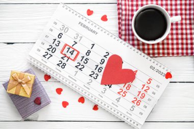 Sevgililer günü için takvimli kompozisyon, beyaz ahşap arka planda bir fincan çay, düz uzanma.