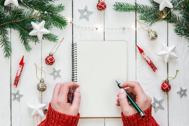 Beyaz not defteriyle birlikte Noel arkaplanı. Güzel kadın elleri, bir kız planlar yazar, gelecek için hedefler, düzlük.