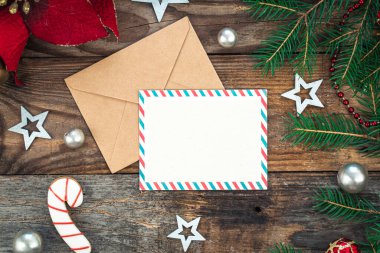 Boş kağıt, zarf, ladin dalları ve ahşap arka planda samimi Noel dekorasyonu ayrıntıları, düz uzanma.