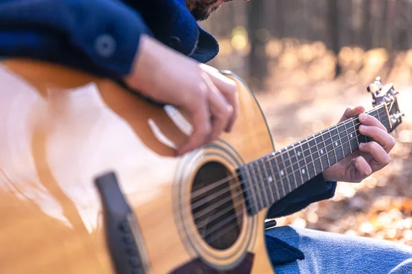 近距离观察 一个男人在寒冷的季节在森林里弹奏吉他 — 图库照片
