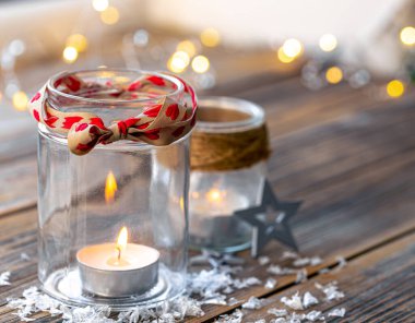 Bulanık arkaplanda cam kavanozlarda mumlarla Noel kompozisyonu, boşluğu kopyala.